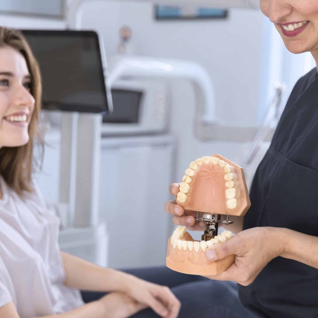 dentist-showing-teeth-model-smiling-patient-1-scaled